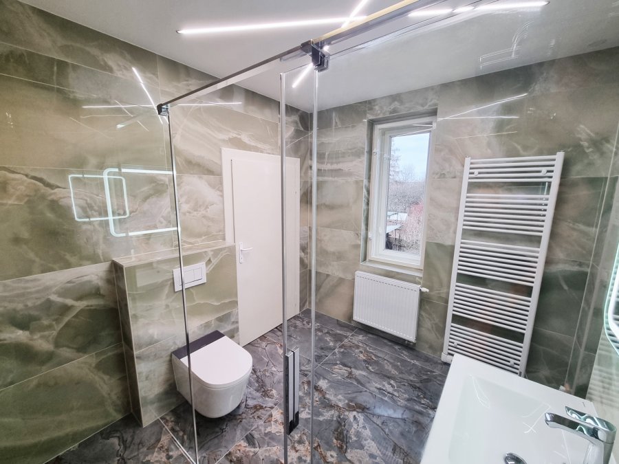 Okno s výhledem do zahrady, radiátor KORADO RADIK, zelenošedé mramorové obklady UNICA Jade Green. Rekonstrukce koupelny, kuchyně a interiéru bytu Svitavy, Hradec Králové | Pemtrade.cz