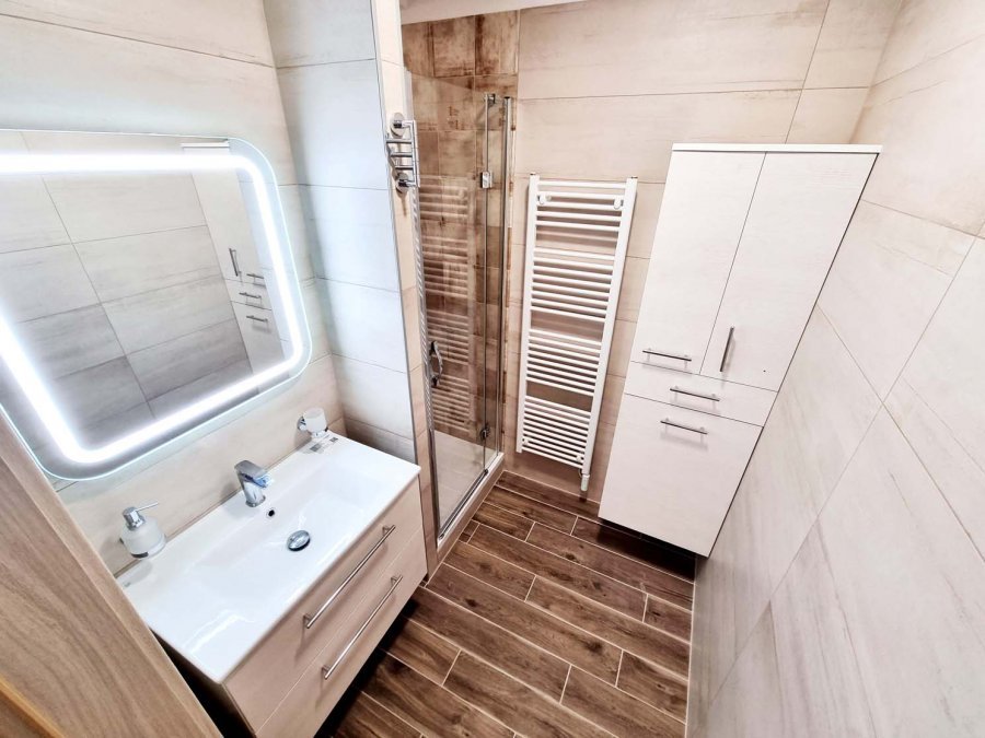 Pohled na koupelnu s topným tělesem KORADO KORALUX, skříní INTEDOOR UNI a dlažbou Woodlike Beige 15×90 Rekonstrukce interiérů, koupelen a kuchyní Svitavy, Hradec Králové | Pemtrade.cz