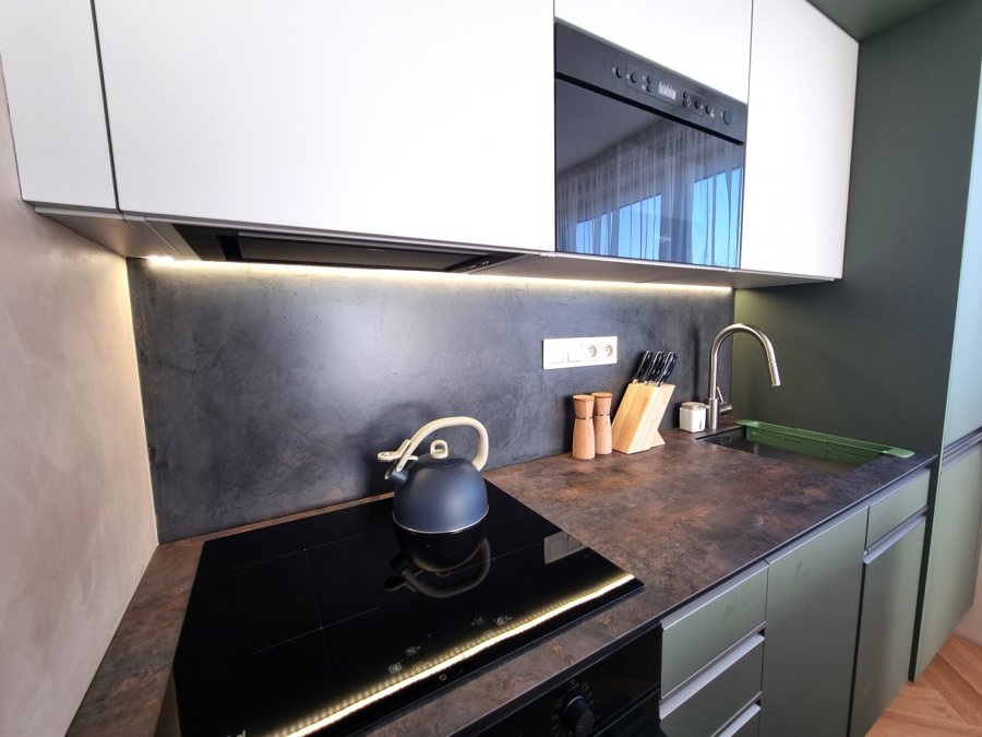 Detail kuchyňské pracovní plochy s varnou deskou, dřezem a podsvícenou zástěnou | Realizace kuchyně a interiéru byt Svitavy, Hradec Králové | Pemtrade.cz