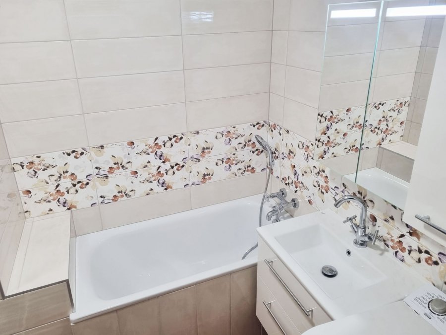 Kompaktní vana Kaldewei Advantage o rozměru 140 × 70 cm s nástěnnou baterií SAPHO AXIA je zasazena do prostoru, kde květinový obklad Rako  Majolika dodává měkkost a ženský tón. Rekonstrukce interiérů, koupelen a kuchyní Svitavy, Hradec Králové | Pemtrade.