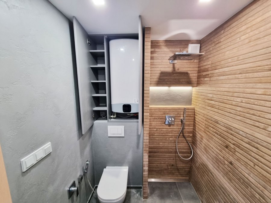 Sprchový kout Riho s obkladem imitujícím dřevo a nikou s LED osvětlením, vybavený podomítkovou termostatickou baterií GROHE SmartControl. Betonová stěrka přechází na vedlejší stěny. Rekonstrukce  interiérů, koupelen a kuchyní Svitavy, Hradec Králové | Pem