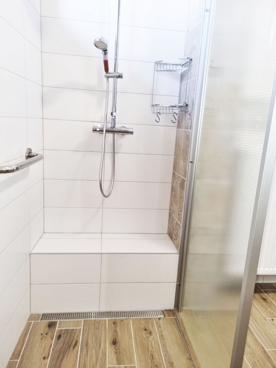 Detail lavice ve sprchovém koutě s keramickou dlažbou a liniovým odtokem. Rekonstrukce interiérů, koupelen a kuchyní Svitavy, Hradec Králové | Pemtrade.cz.