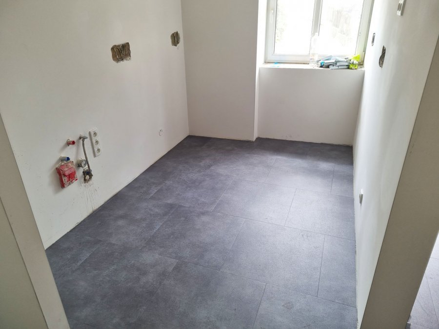 Výklenek budoucí kuchyně s čerstvě položenou dlažbou MB Keramika GC 05, připravené instalace pro dřez a spotřebiče. Rekonstrukce interiérů, koupelen a kuchyní Svitavy, Hradec Králové | Pemtrade.cz.