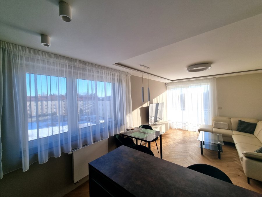 Pohled z kuchyně do obývací části s velkými okny, jídelním koutem a krémovou rohovou sedačkou | Realizace kuchyně a interiéru byt Svitavy, Hradec Králové | Pemtrade.cz