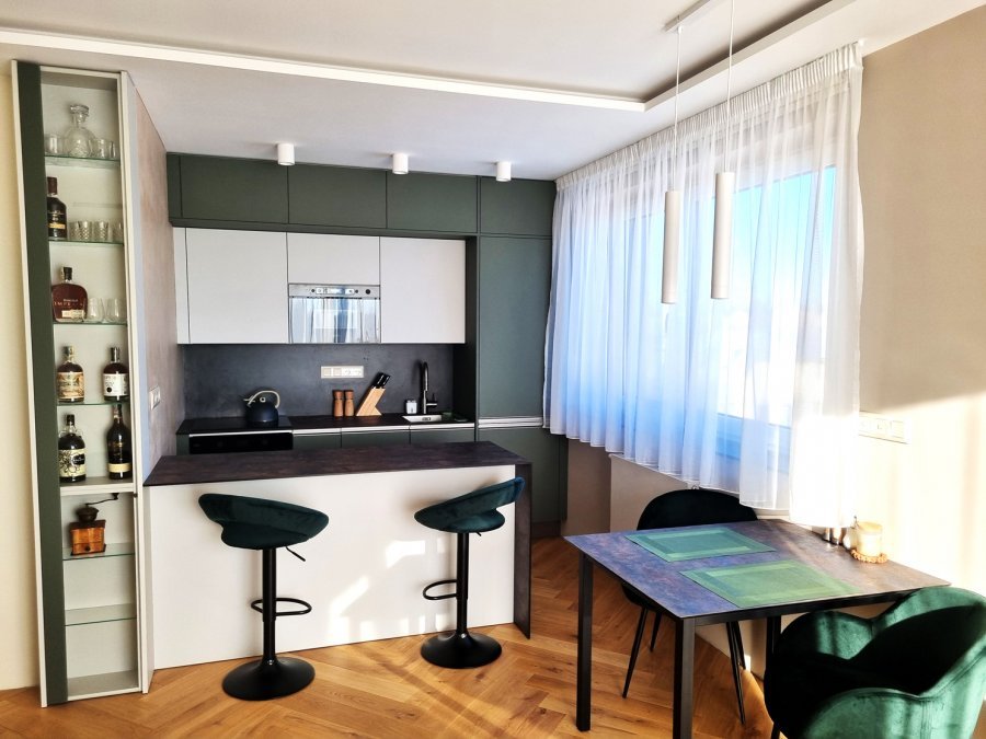 Kuchyně s olivově zelenou linkou, barovým pultem a jídelním stolem v odlehčeném duchu gentleman’s club | Realizace kuchyně a interiéru byt Svitavy, Hradec Králové | Pemtrade.cz