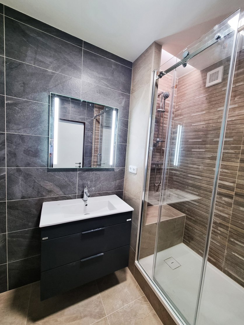 Koupelna s kombinací velkoformátové dlažby Halley Taupe 60×60 a tmavého obkladu v imitaci kamene. Realizace koupelny a interiéru Svitavy, Hradec Králové | Pemtrade.cz