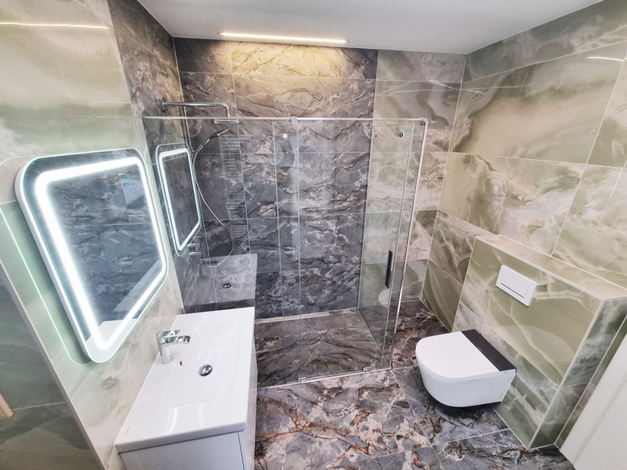 Ucelený pohled na koupelnu s LED zrcadlem, umyvadlem Geberit iCon Light a výraznou mramorovou kresbou na podlaze. Rekonstrukce koupelny, kuchyně a interiéru bytu Svitavy, Hradec Králové | Pemtrade.cz