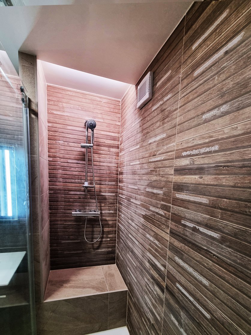 Detail sprchové části s baterií HERZ FRESH termostatickou a strukturovaným obkladem v imitaci dřeva. Realizace koupelny Svitavy, Hradec Králové | Pemtrade.cz