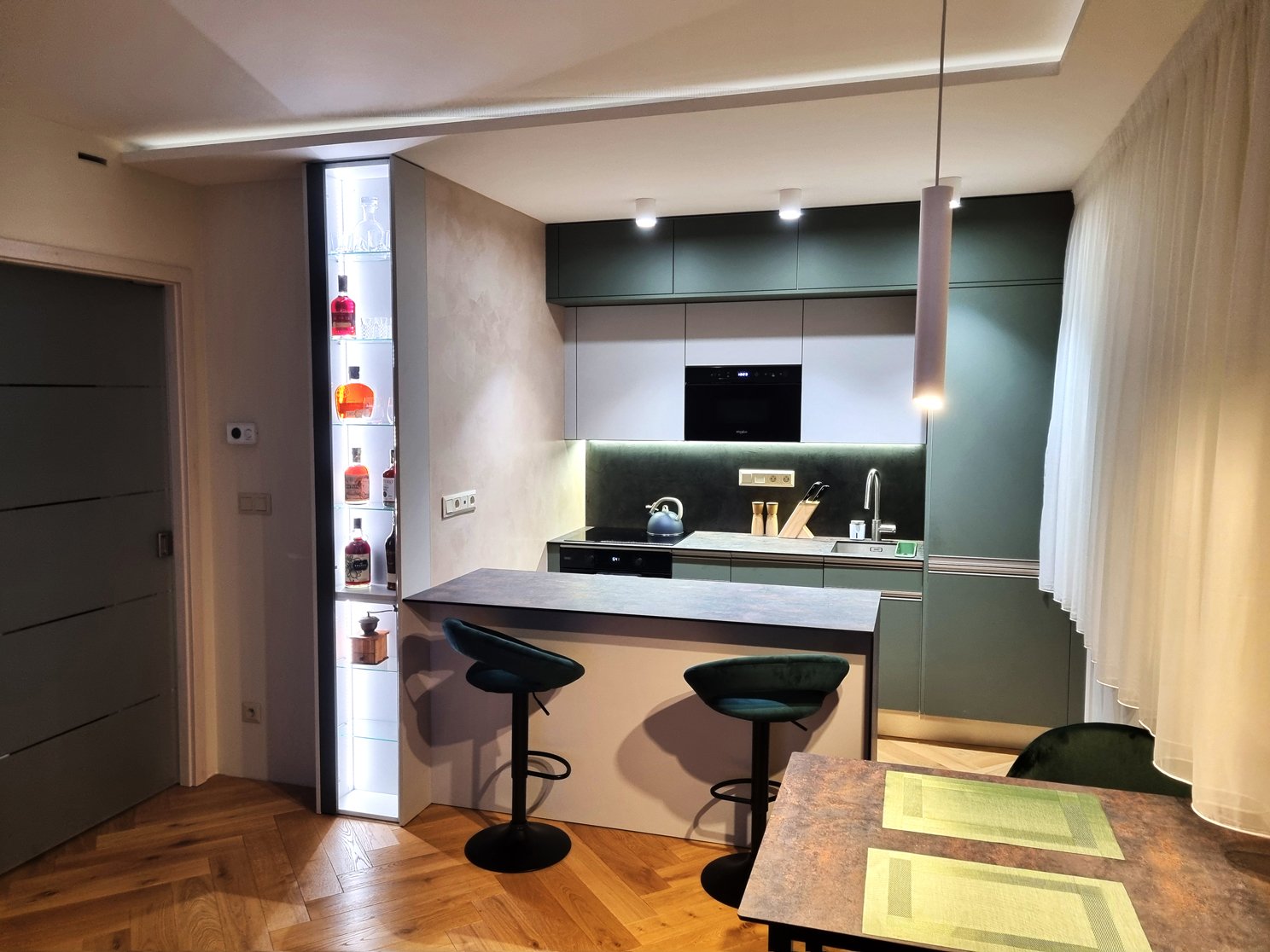 Kuchyně s barovým pultem, olivově zelenou linkou a ambientním osvětlením ve večerním režimu | Realizace kuchyně a interiéru byt Svitavy, Hradec Králové | Pemtrade.cz